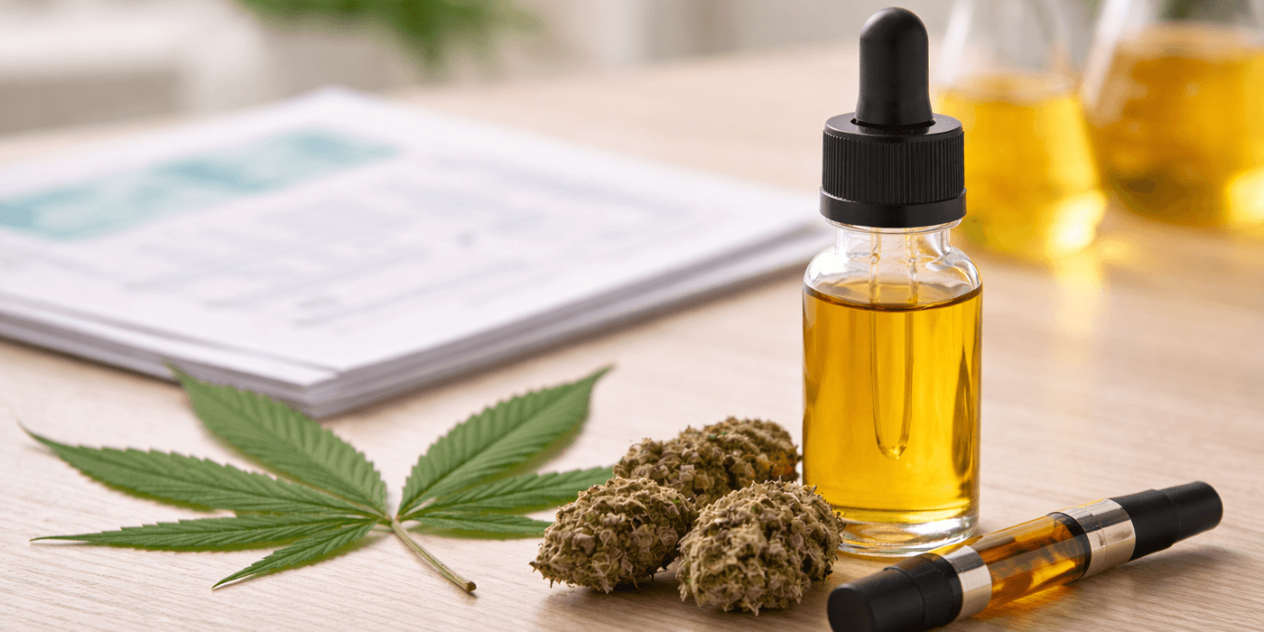 Cannabis oil dropper bottle with dried flower, vape cartridge, and cannabis leaf on tabletop near paperwork., cannabis oil research